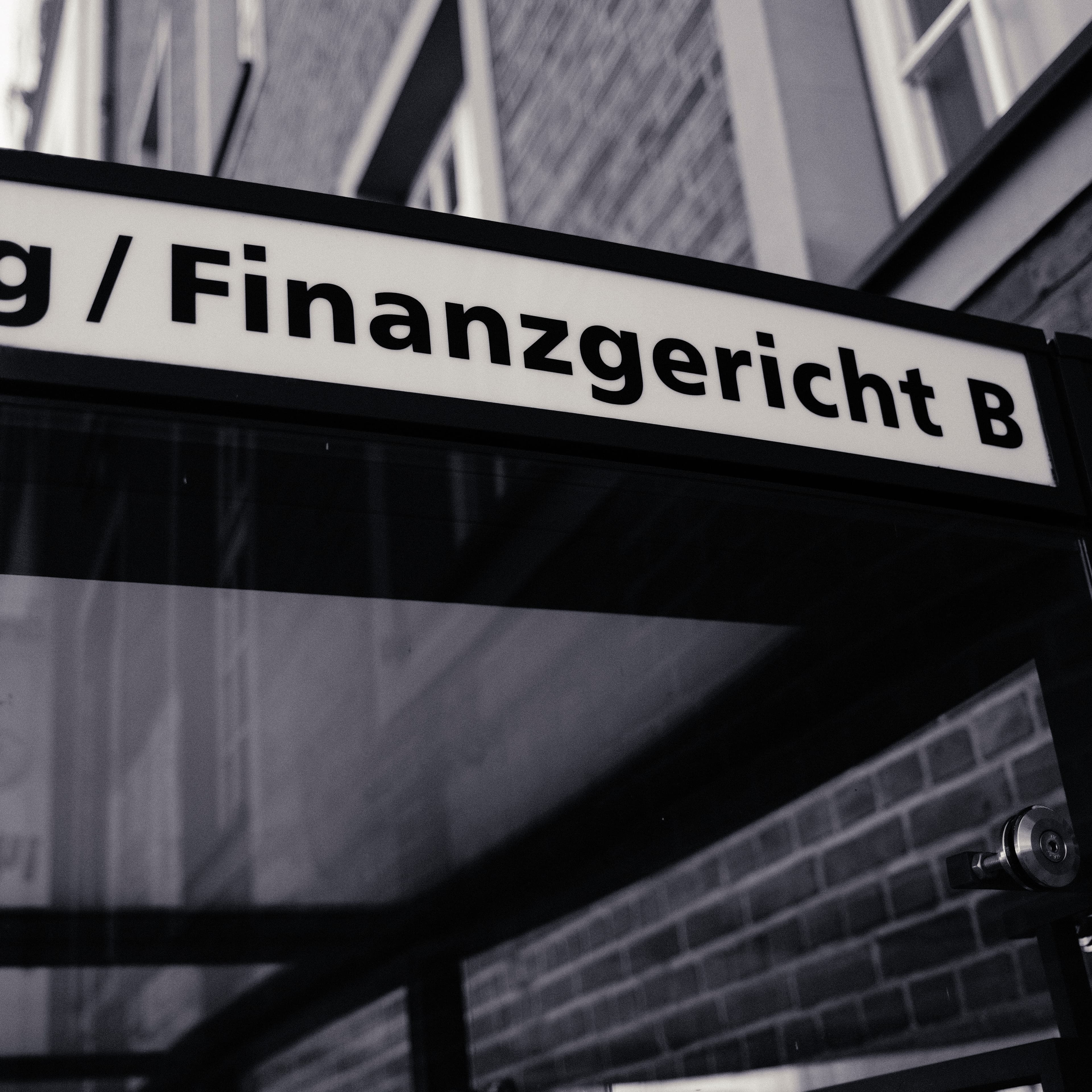Illuminated sign reading “Finanzgericht B”, photographed from below.